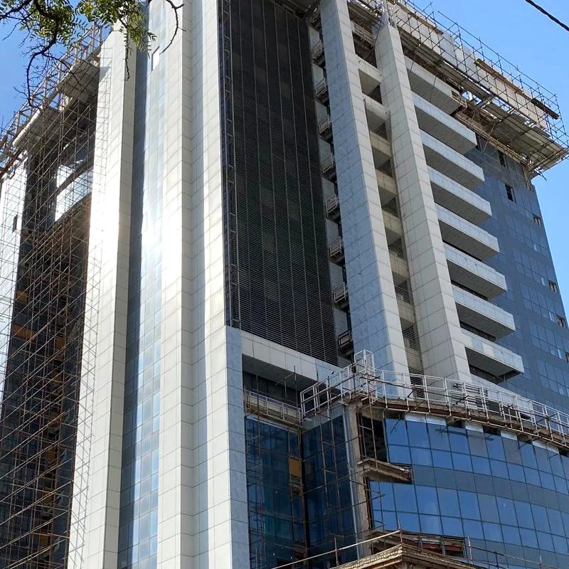 Close view of white vertical fins against dark glass on a tower under construction.